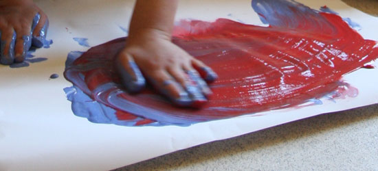 Hand of a child finger painting on paper