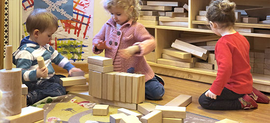 Three children playing with wooden blocks