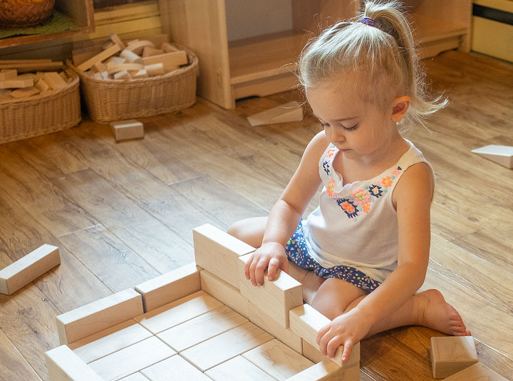 A girl is building a house out of wooden blocks