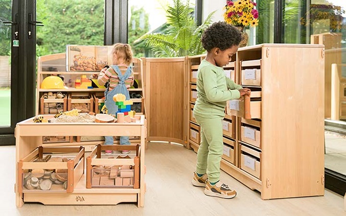 Two young children play with various pieces of furniture.