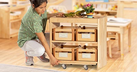 A teacher adjusts the wheels on a shelf.