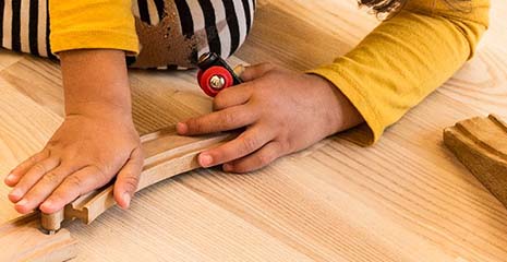 A child is playing with a wooden toy train