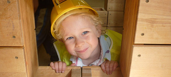A child with hard hat peeking out of a hollow block building