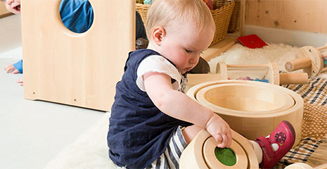 Toddler engaged in heuristic play with round wooden objects