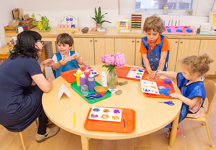 Nursery teacher with three young children around a table