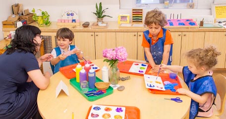 Nursery teacher with three young children around a table