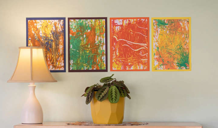 Four acorn paintings, nicely arranged on a wall behind a lamp and a potted plant.