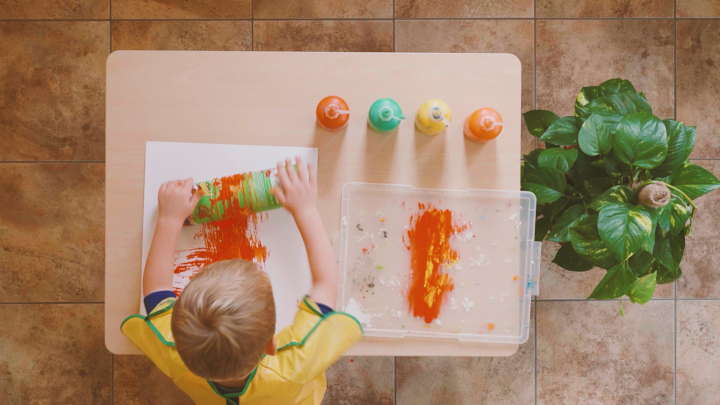 child using pringles can with string to roll paint on paper