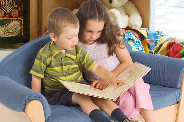 girl and boy reading on low blue sofa