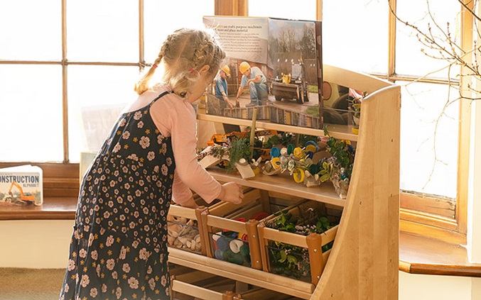 A girl looks on a shelf for materials