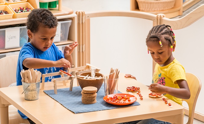 Two children at a table experiment with loose parts