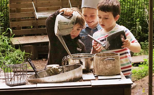 three boys playing outside with watering cans