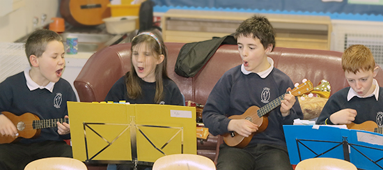 primary school children singing and playing ukuleles