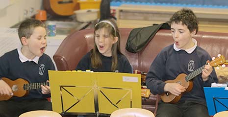 three children playing ukuleles and singing