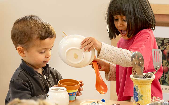 Two preschool children collaborating at the kitchen island.