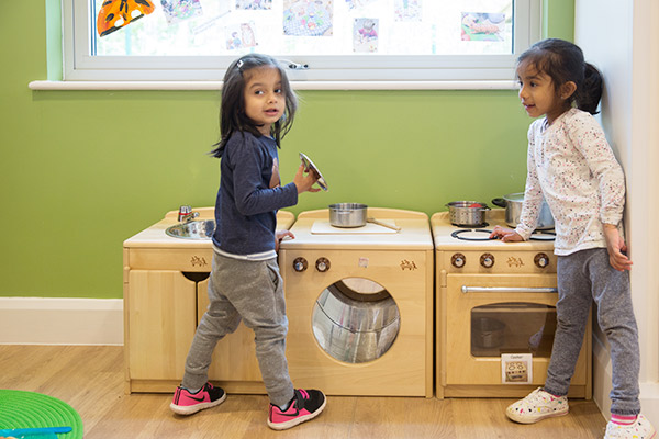 two reception age children playing in the home corner