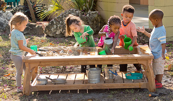 a group of small children playing around a water play table
