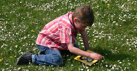 Boy on meadow engaged in outdoor maths activity