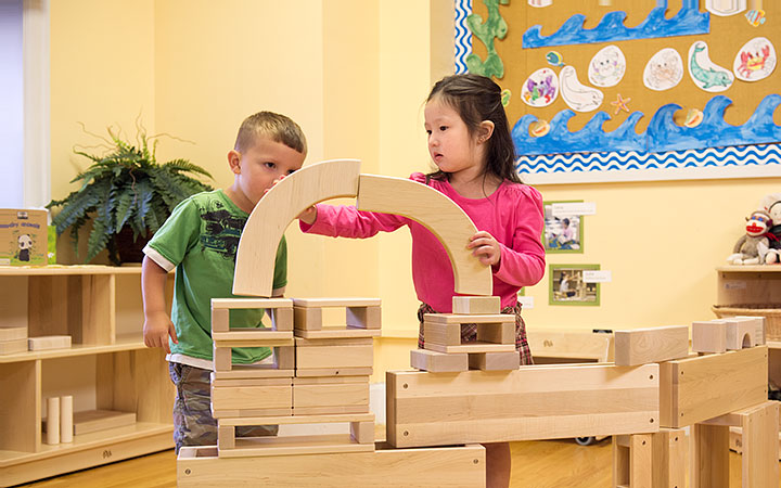 A boy is being the onlooker as a girl plays with unit blocks