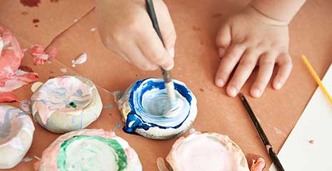 Flat rocks being painted by a child