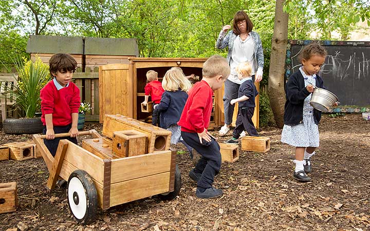 A boy pushes a wheelbarrow loaded with wooden blocks