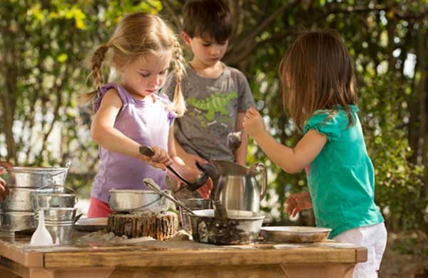 children playing with mud and natural materials at an outlast table