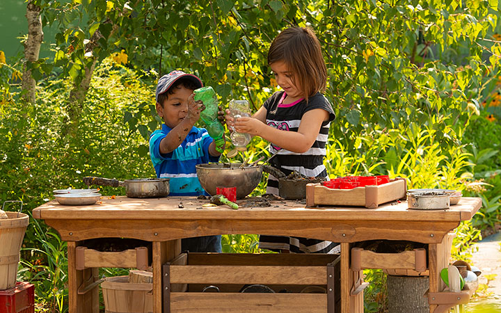 a girl is mixing mud in an old pan with her hands