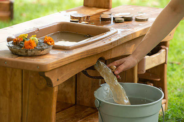 opening the plug of a mud kitchen kink to drain the muddy water