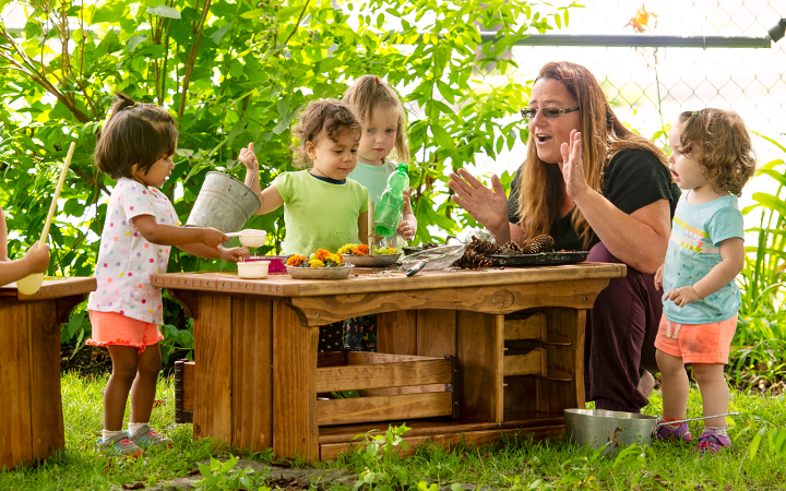 two children decorating their mud pies with yellow flowers