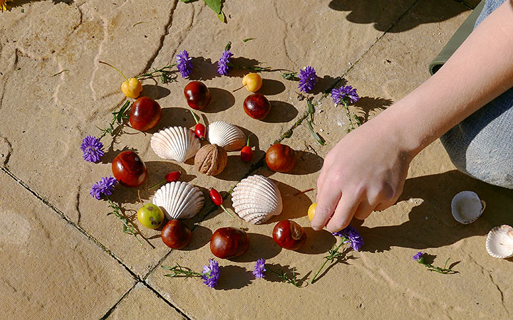 child’s hand adding crab-apple to nature pattern