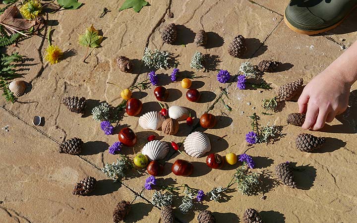 child’s hand adding crab-apple to nature pattern