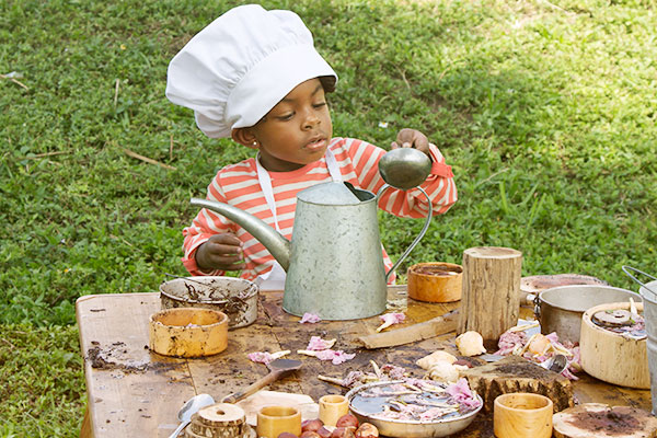 child playing at a table with mud and loose parts