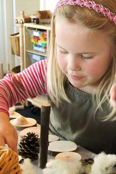 young girl playing at a table with natural loose parts