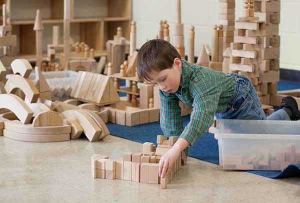 a boy building a tower with unit blocks