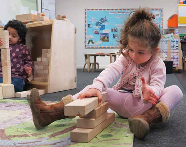 a girl constructing a tower with unit blocks