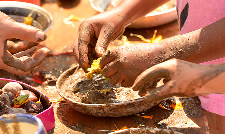 children’s hands playing with mud in dishes