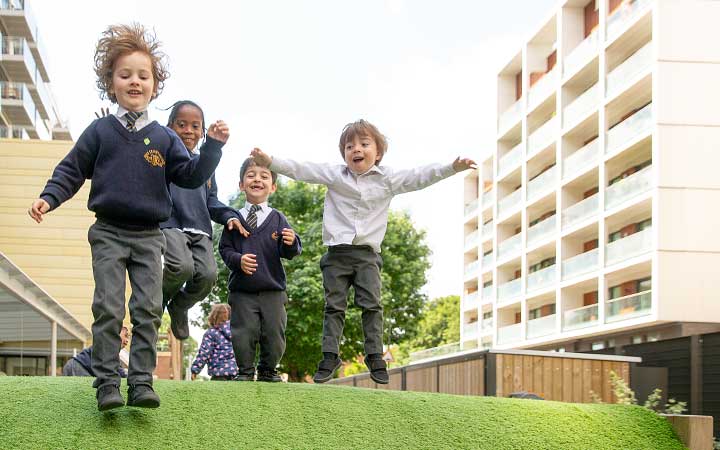 Chrildren jumping and running down a hill in a school outdoors area