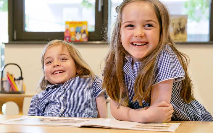 Two primary school children sitting at a desk and laughing