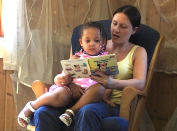 an adult reading a story to a toddler aged girl
