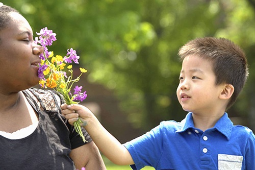 boy holding flowers for teacher to smell