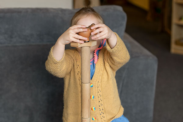 Child building a block tower with a toy animal on top