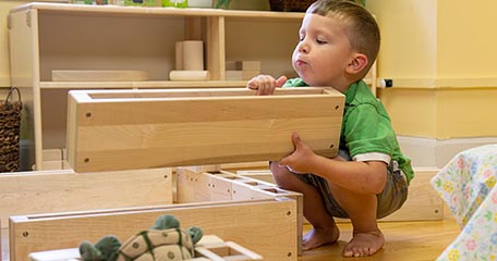 a toddler building with wooden blocks