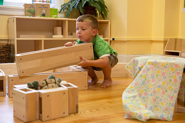 A small child building an enclosure with mini hollow blocks