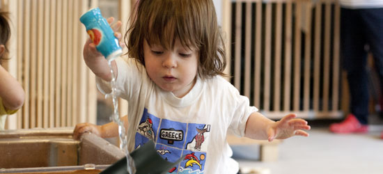 young child pouring water into a gutter