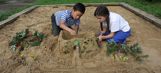two children playing in a large sandpit