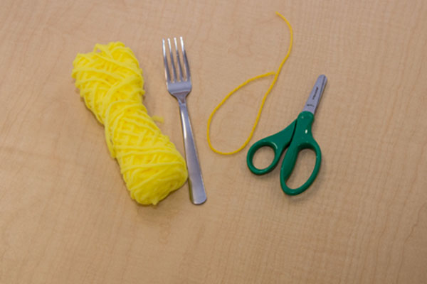 yellow yarn, a fork and a pair of scissors