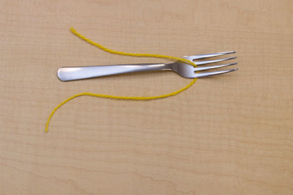 a length of yarn between the middle tines of a fork