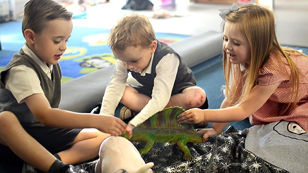 three children talking about a toy dinosaur