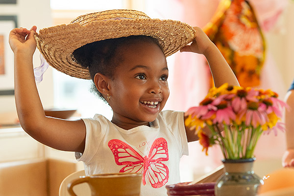 Young child playing with straw hat