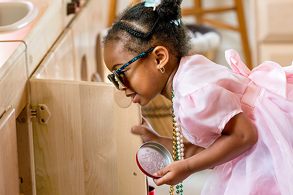 Child looking into cupboard while doing role-play